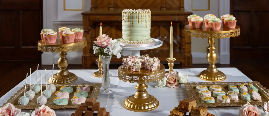 A lavish wedding dessert table adorned with popsicles, fudge, cupcakes, treats, macarons and more
