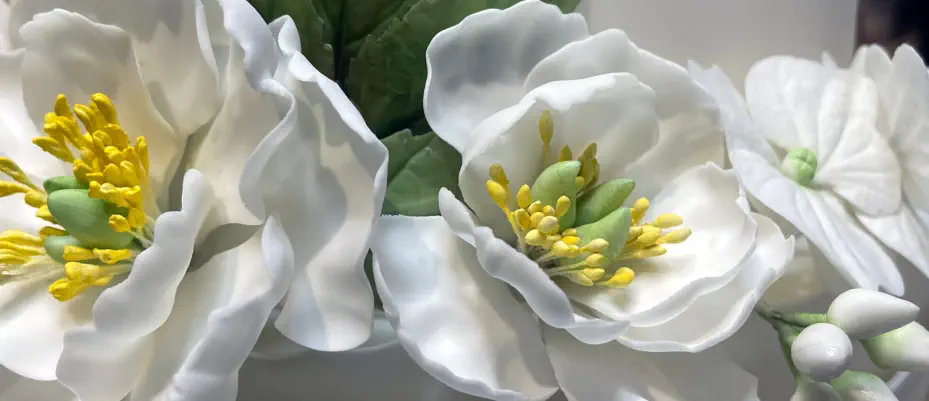 Delicate sugar flowers, meticulously crafted by hand, grace the wedding cake, enhancing its beauty and creating a luxurious ambiance